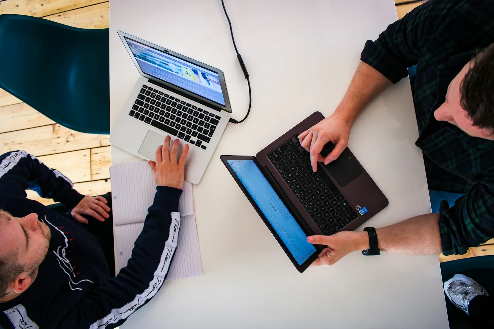 Due professionisti lavorano a un tavolo con computer portatili in ufficio.
