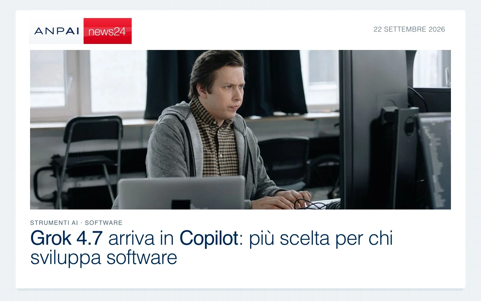 Una persona lavora a una scrivania con un computer portatile e un monitor in un ufficio.