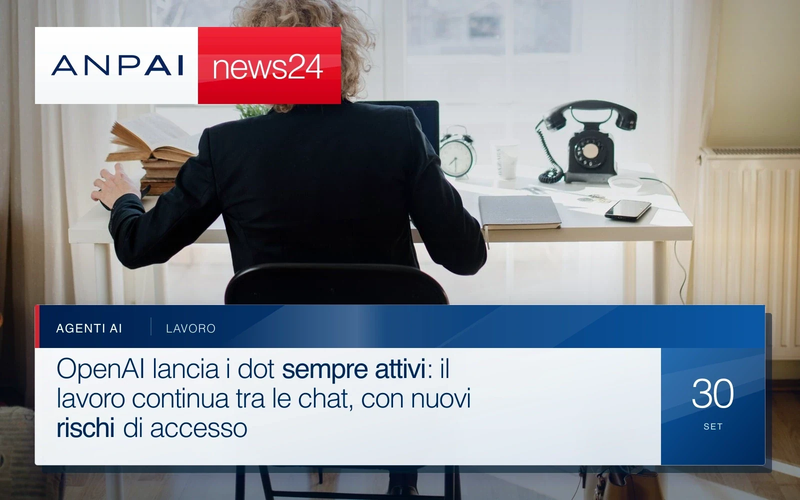 Una persona seduta alla scrivania lavora al computer in una stanza luminosa.